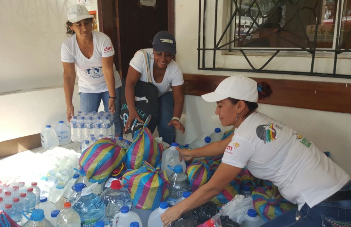 Drei Frauen stehen vor einer Vielzahl an Wasserflaschen.