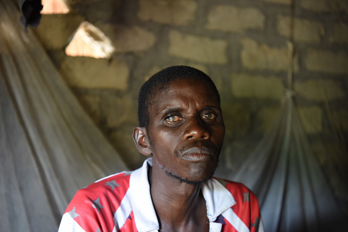 Ein Mann sitzt in einer Hütte. Seine Augen sind getrübt.
