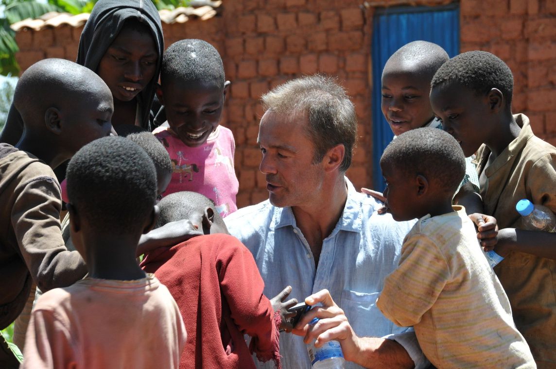 Ein von afrikanischen Kindern umringter Mann