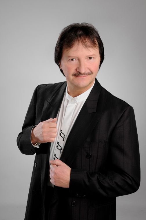 Mann in Jackett und weißem Hemd, dessen Knopfleiste mit Musiknoten bestickt ist