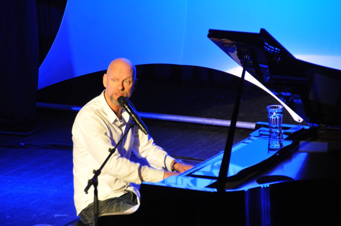 Mann mit Mikrofon am Flügel