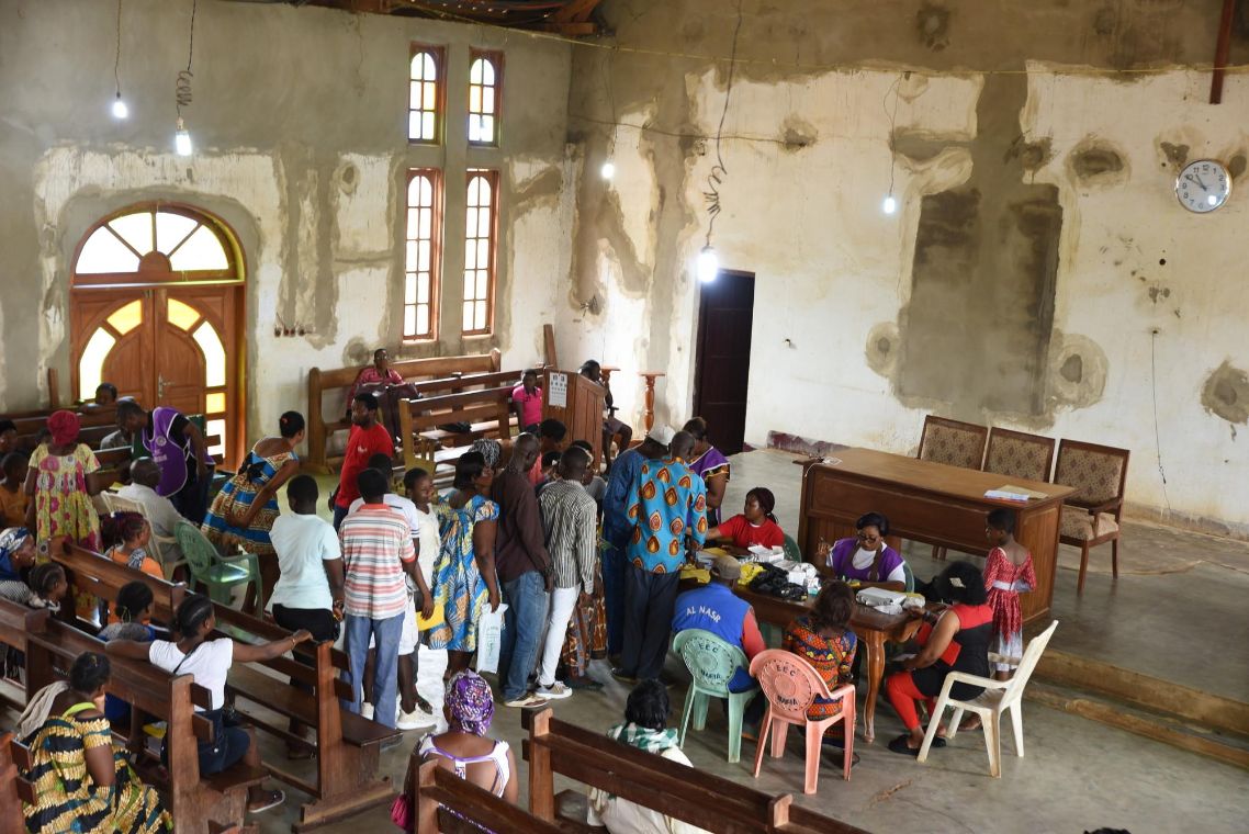 Menschenmenge bildet eine Schlange vor einem Registriertisch in einer Kirche