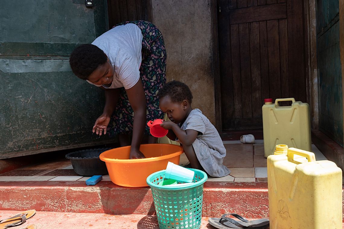 Eine Frau und ein kleines Mädchen spülen Geschirr in einer kleinen Plastikwanne.