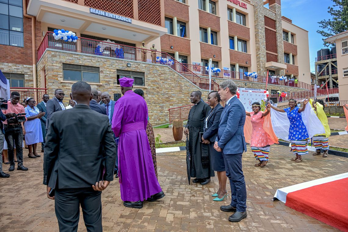 Menschen, darunter tanzende Frauen, auf dem gepflasterten Platz vor einem mehrgeschossigen Gebäude.
