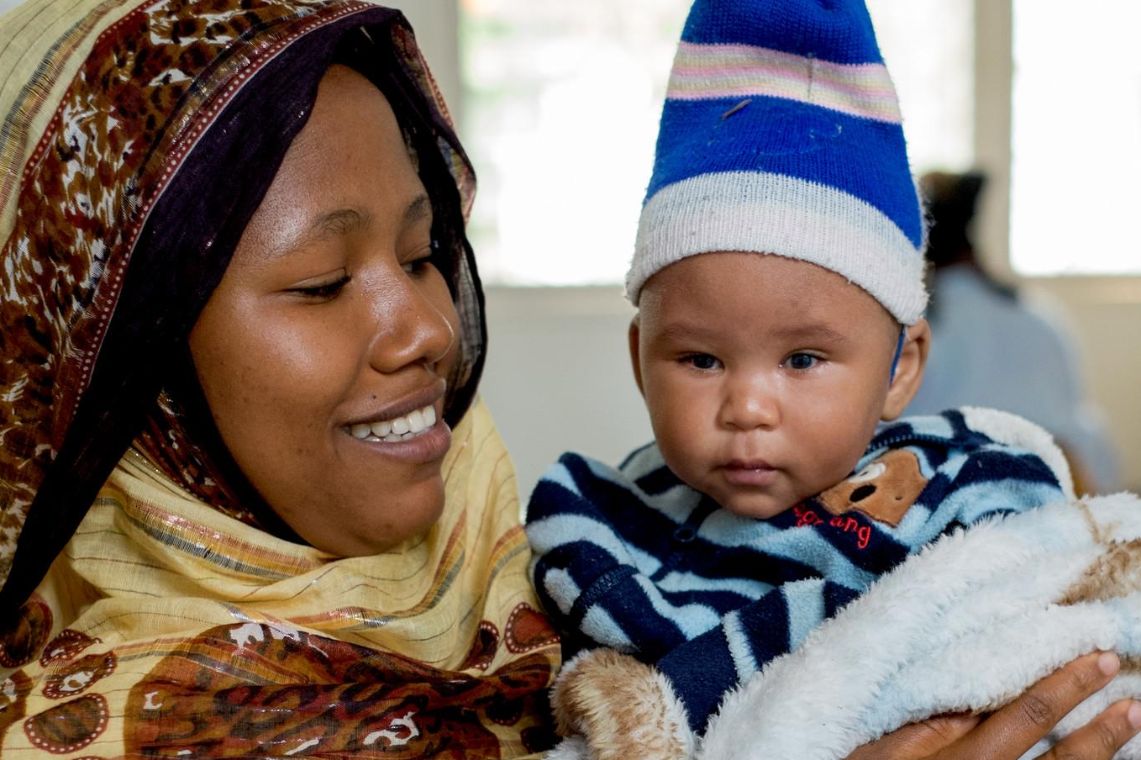 Eine lachende Frau und ein kleiner Junge mit Mütze