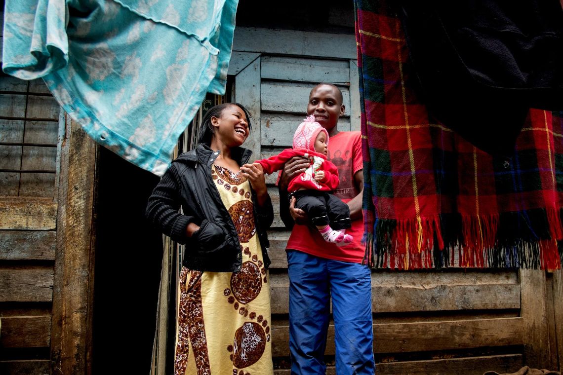 Ein Paar mit einem Baby vor einer Hütte.