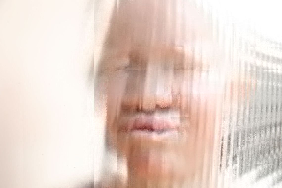 Gesicht einer hellhäutigen afrikanischen Frau hinter einer Strukturglasscheibe