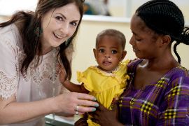 Lachende Frau neben einer afrikanischen Mutter mit kleinem Kind