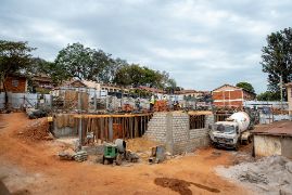 Baustelle, auf der eine Mauer neben einem Baufahrzeug zu sehen ist.