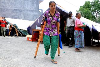 Ein Mädchen geht mit Krücken an Zelten vorbei.