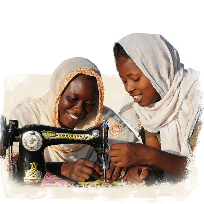 Dank Spendengeschenk Ausbildung arbeitet eine Frau mit einer Nähmaschine, eine zweite leitet sie an.