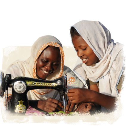 Dank Spendengeschenk Ausbildung arbeitet eine Frau mit einer Nähmaschine, eine zweite leitet sie an.