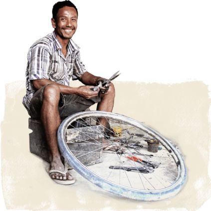 Ein Mann repariert ein Fahrrad - dank Spenden-Geschenk Existenzgründung