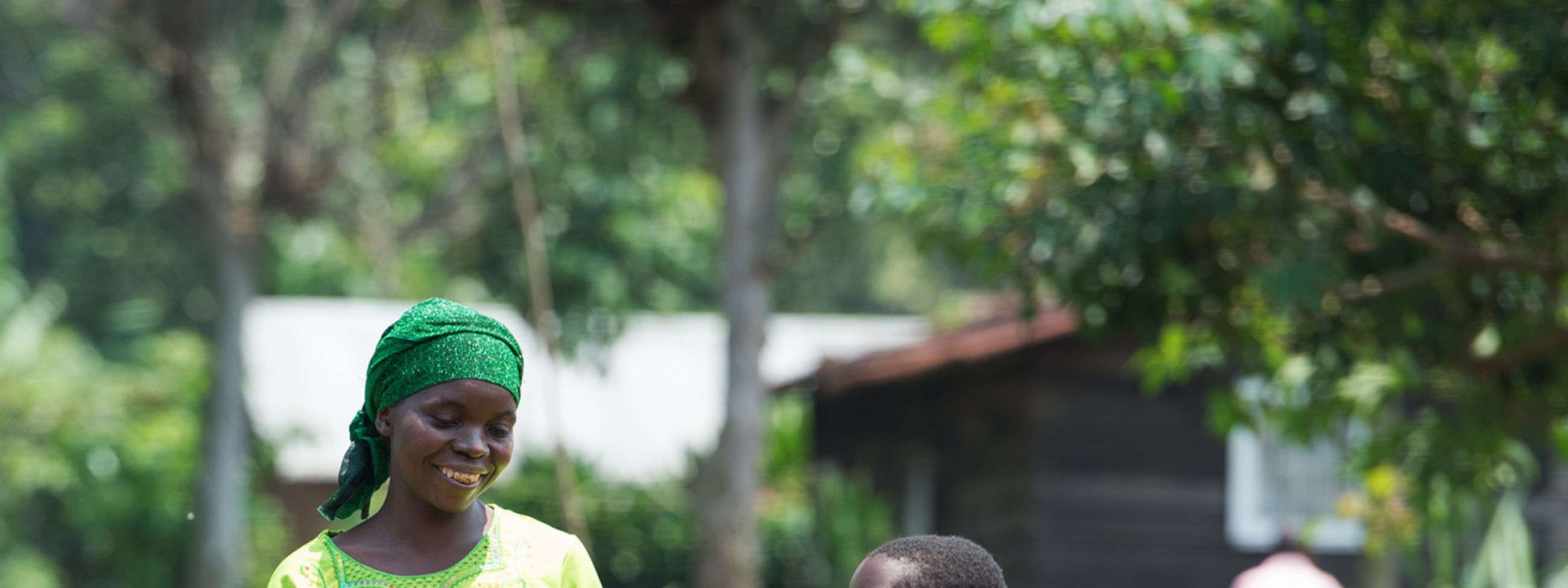 Eine Frau und ein Mädchen gehen Hand in Hand über einen sandigen Weg im Grünen.