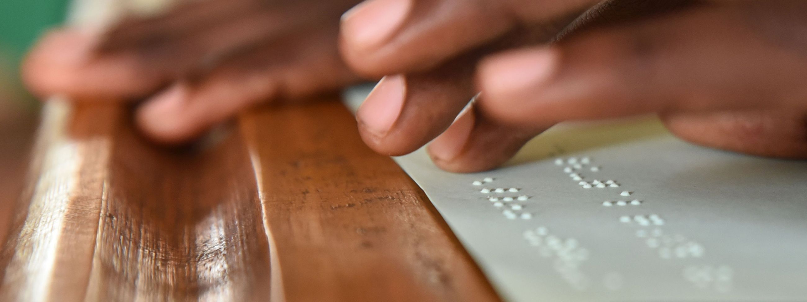 Hände liegen auf den erhabenen Punkten einer Blindenschriftbuchseite.