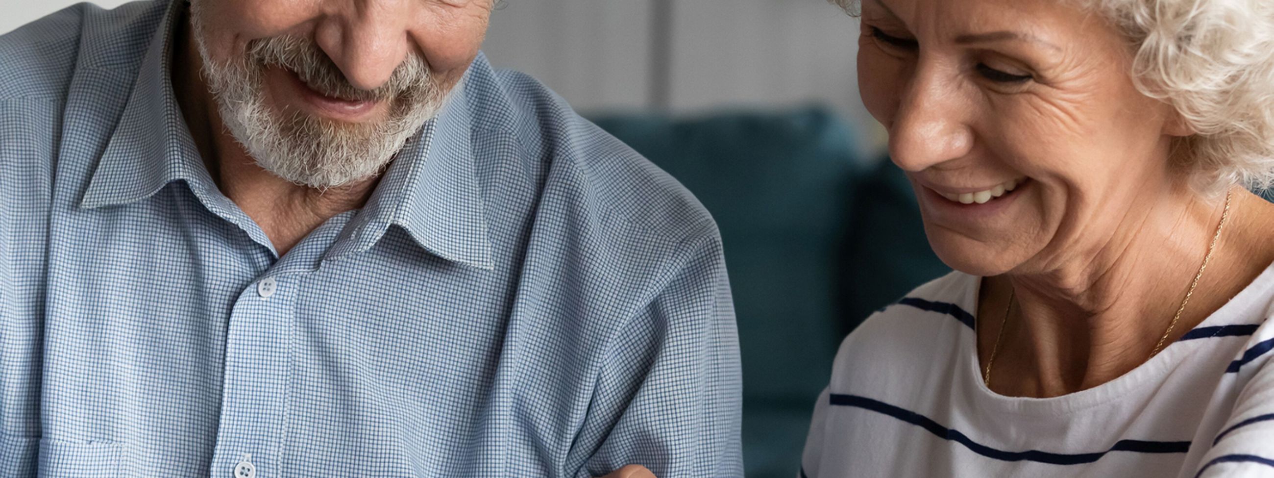 Testamentsspende: Ein älteres Paar sitzt am Tisch. Der Mann hält einen Stift und schreibt auf ein Blatt Papier seine Nachlassspende.
