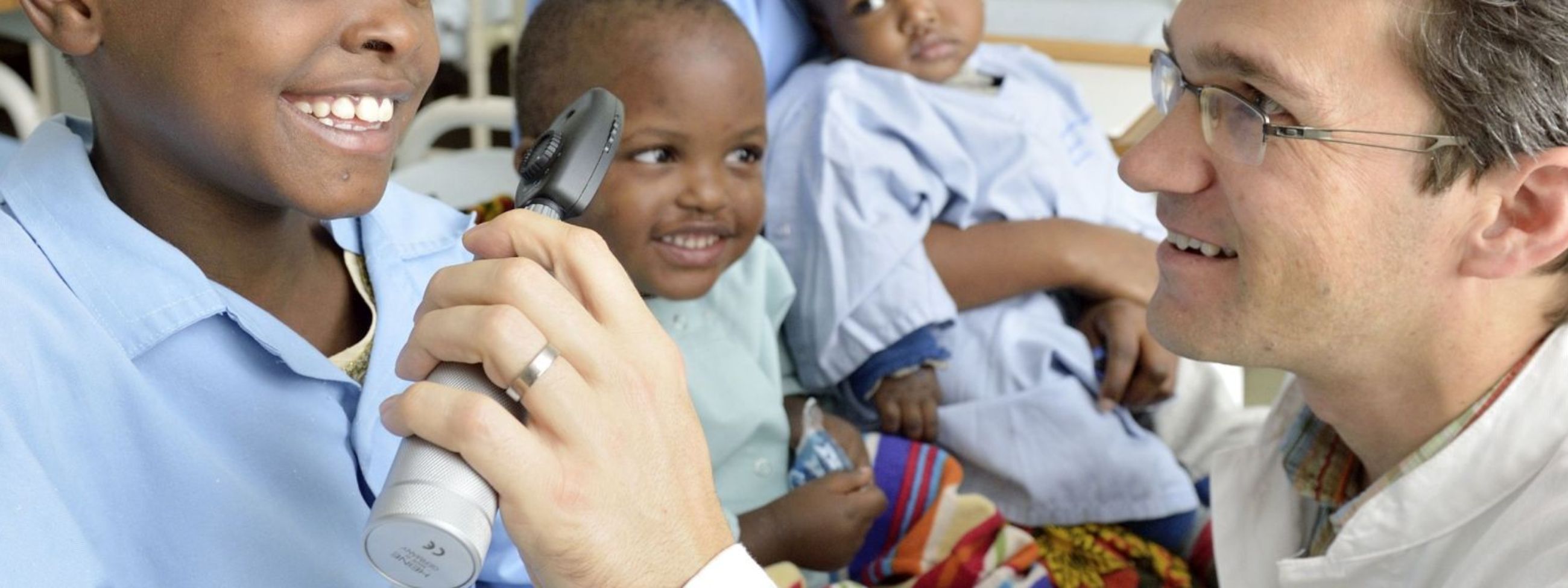 Ein Mann im weißen Kittel untersucht die Augen eines afrikanischen Mädchens