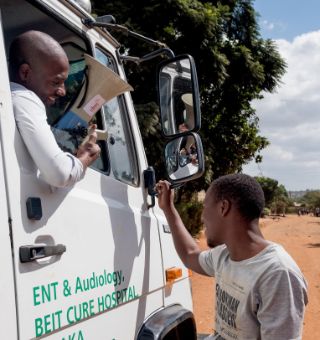 Aus dem Autofenster herausschauender afrikanischer Mann mit Megaphon