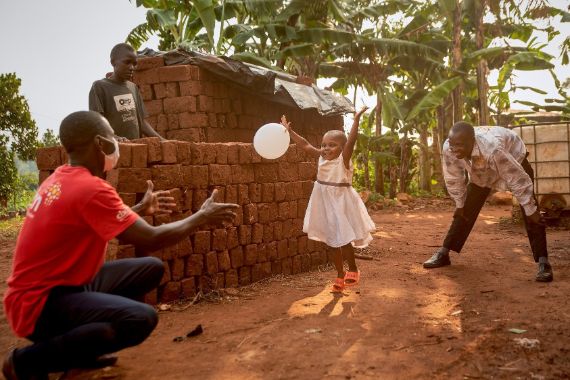 Ein Kind spielt vor einer Mauer mit einem Luftballon.