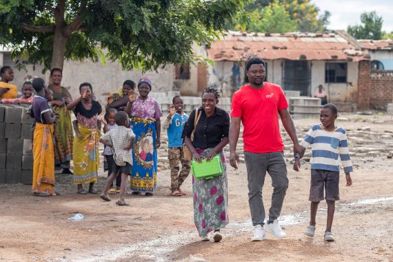 Eine Gruppe winkt einer Frau, einem Mann im T-Shirt mit der Aufschrift &quot;CBM&quot; und einem Jungen nach.