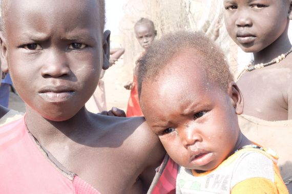 Ein kleiner Junge hält ein etwa zweijähriges Kind auf dem Arm.