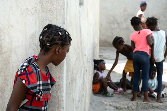 Ein Mädchen schaut um eine Häuserecke, wo Kinder spielen.