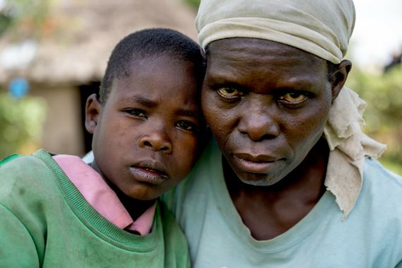Ein Mädcehn legt den Kopf ans Gesicht einer Frau mit Kopftuch.