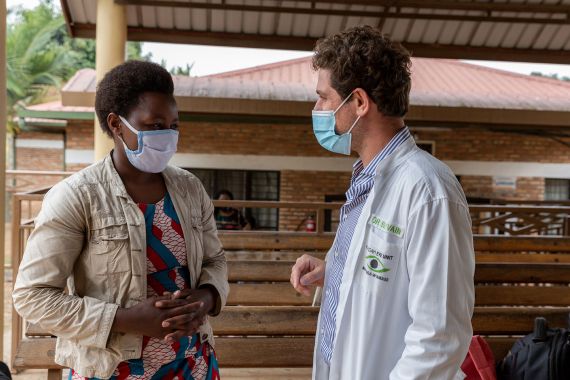 Arzt und Patientin unterhalten sich miteinander. Beide tragen einen Mundschutz.