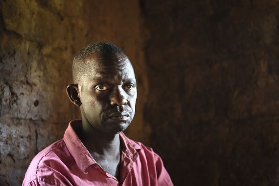 Porträt eines Mannes in einem spärlich beleuchteten Raum.