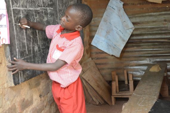 Ein Junge schreibt mit Kreide auf eine Wandtafel.