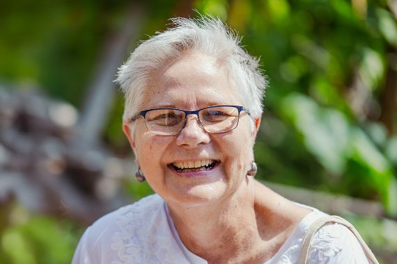 Lachende Frau mit grauem Kurzhaarschnitt.