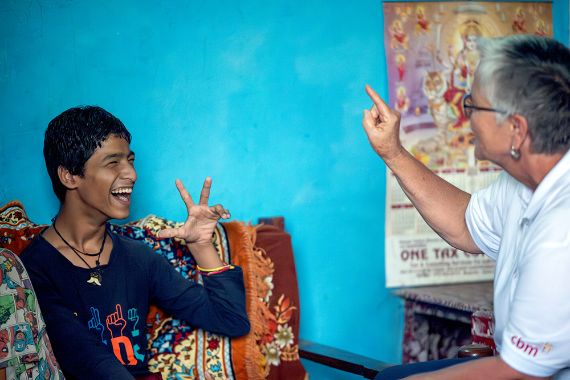Lachende Frau mit grauem Kurzhaarschnitt.