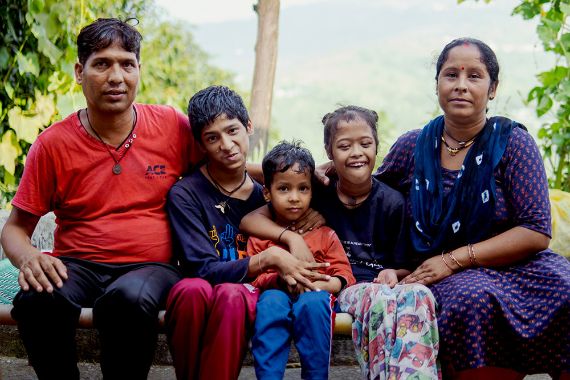 Ein Mann und eine Frau sitzen auf einer Bank, zwischen ihnen drei Kinder.