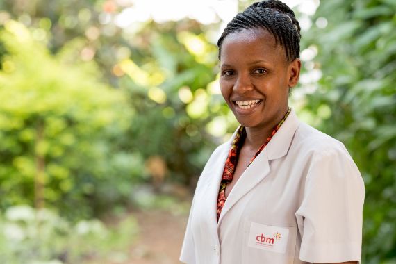 Eine junge Frau im weißen Kittel. Ihr Haar ist zu Zöpfchen geflochten und hochgesteckt.