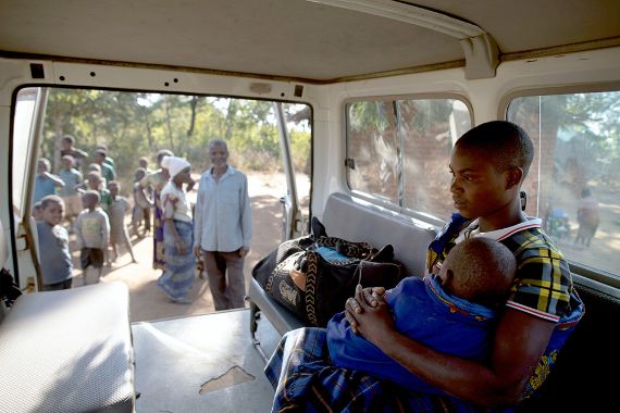 Eine junge Frau mit einem Kleinkind auf dem Schoß sitzt in einem kleinen Bus.