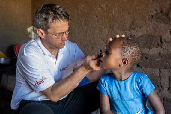 Augenarzt und ein Mädchen an den Augen in ihrem Zuhause.