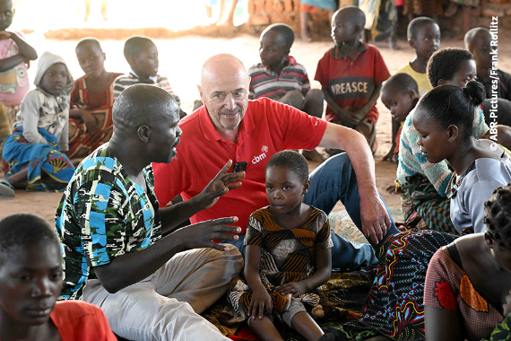 Eine Gruppe von Menschen sitzt auf de, Boden. 