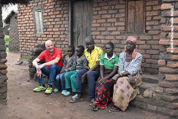 Sechs Personen sitzen vor einer Hütte.