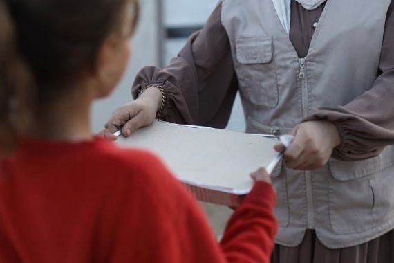 Eine Person gibt einem Kind eine Aluschale in die Hände.