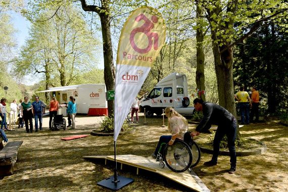 Eine Rollstuhlnutzerin wird von einem Mann über eine Rampe geschoben