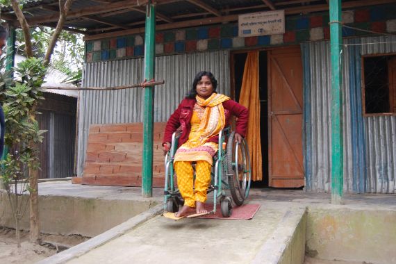 Eine Frau im Rollstuhl fährt die Rampe vor einem Haus hinunter.