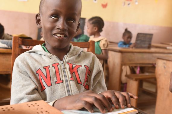 Sehbehinderter Junge ertastet mit seinen Fingern die Blindenschrift Braille.