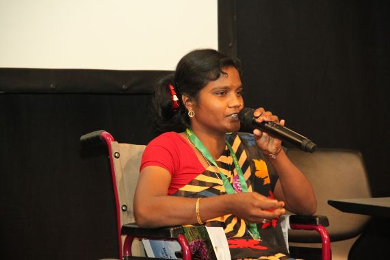 Eine Fau im Rollstuhl spricht in eine Mikrophon