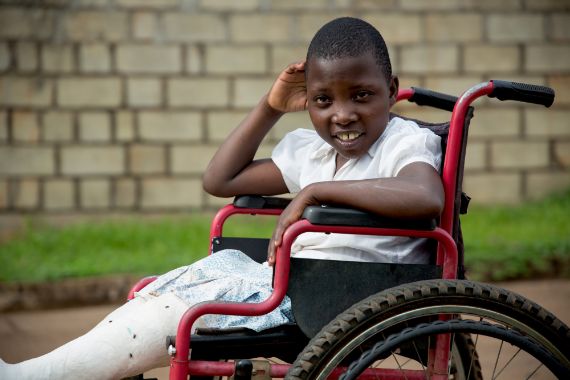 Ein afrikanisches Mädchen sitzt in einem Rollstuhl.