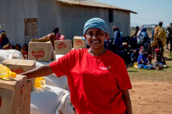 Eine Frau steht neben Hilfsgütern.