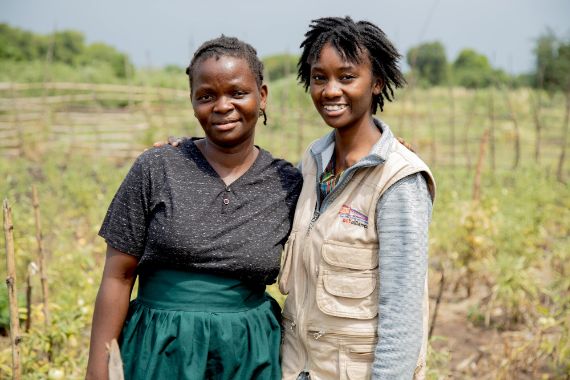 Zwei Frauen stehen Arm in Arm auf einem Feld.