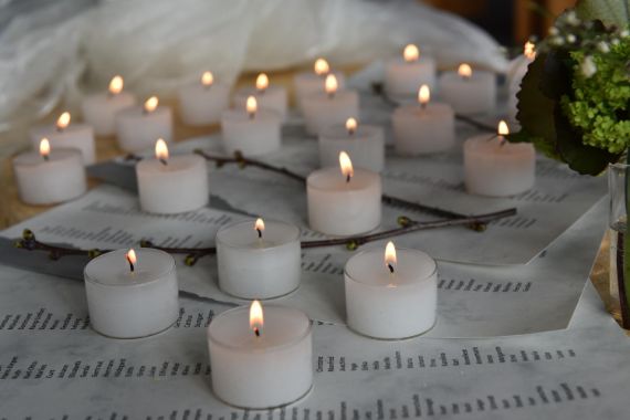 Brennende Teelichte stehen neben Zetteln mit Namen und Orten zum Gedenken an Nachlassspender.