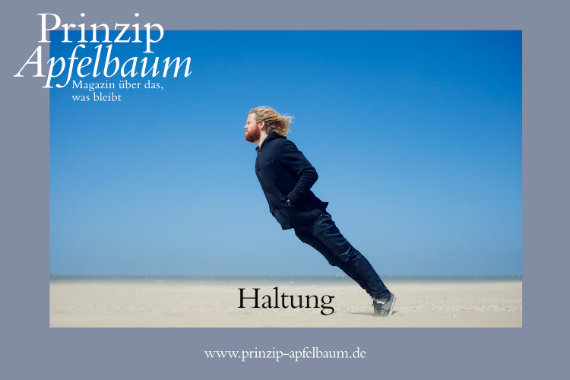 Ein Mann mit Bart und langem Haar lehnt sich gegen den Wind.