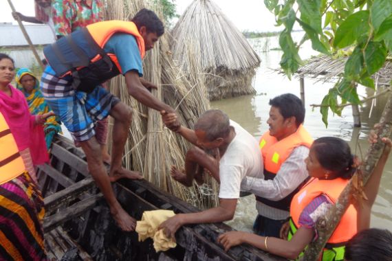 Rettungskräfte helfen einem Mann während einer Überschwemmung in ein Boot.