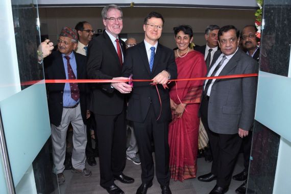 Zwei Männer durchtrennen ein rotes Band, daneben stehen weitere Menschen